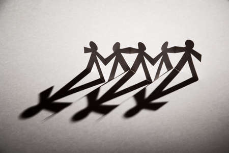 Line of cutout paper dolls throwing a shadowの写真素材