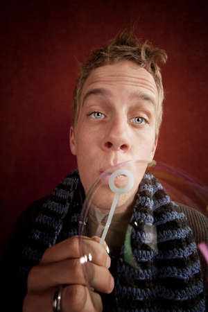 Handsome young blonde man blowing a bubbleの写真素材
