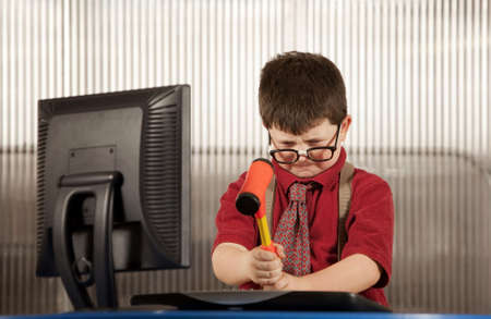 Nerdy young boy smashing his computer with a hammer