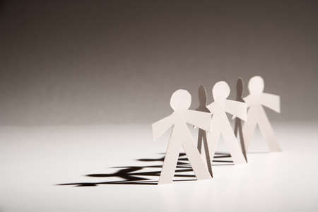 Line of cutout paper dolls throwing a shadowの写真素材