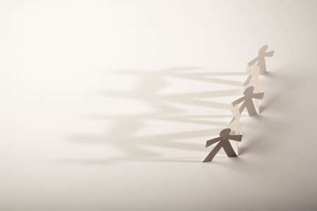 Line of cutout paper dolls throwing a shadowの写真素材
