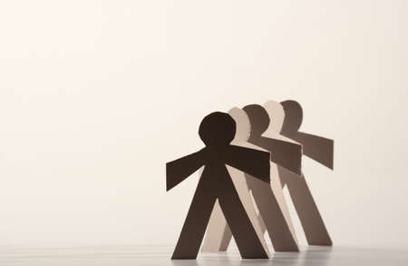 Line of cutout paper dolls throwing a shadowの写真素材