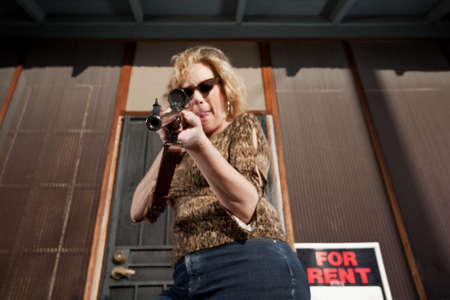 Blonde woman on her front porch with a rifleの写真素材