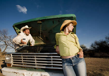 Man and woman in cowboy hats with old truckの写真素材