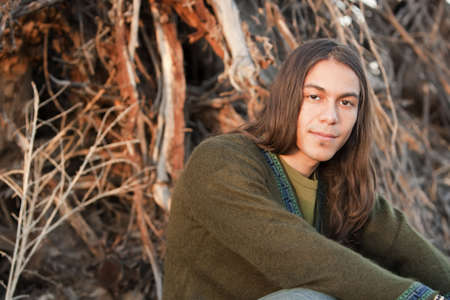Handsome young man with long hair in an outdoor settingの写真素材