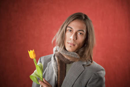 Closeup Portrait of a Handsome Young Man with Yellow Tulipの写真素材