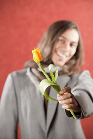 Closeup Portrait of a Handsome Young Man with Yellow Tulipの写真素材
