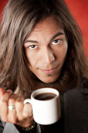 Closeup Portrait of a Handsome Young Man with Long Hair Drinking Coffeeの写真素材