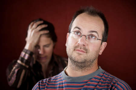 Guilty man with upset woman in the backgroundの写真素材