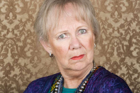 Portrait of skeptical senior woman in front of gold backgroundの写真素材