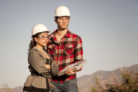 Handsome man and pretty woman outdoors wearing protective hardhatsの写真素材