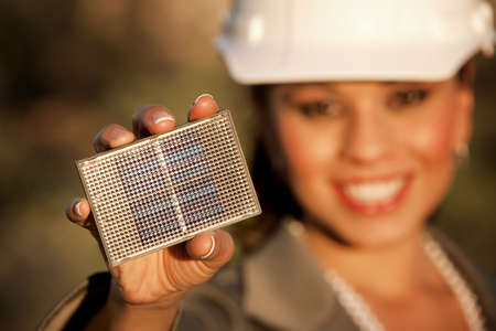 Pretty young woman wearing hardhat with small solar panel in handの写真素材