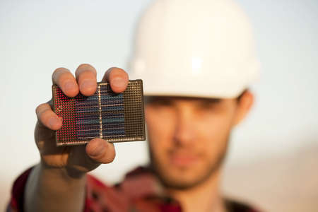 Handsome young man wearing hardhat with small solar panel in handの写真素材