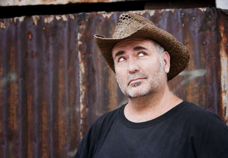 Mature man with gray stubble in a cowboy hat