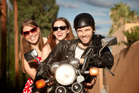Three young adults posing on vintage motorcycleの写真素材