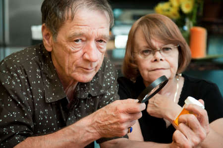 Senior couple closely examining instructions on prescription medicationsの写真素材