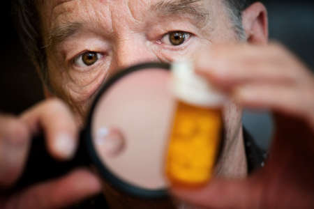 Man closely examing instructions on prescription medicationsの写真素材