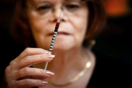 Senior woman looking at small hypodermic needleの写真素材