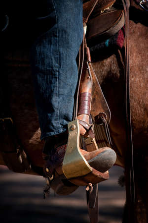 Cowboy leg and foot in stirrup on horseの写真素材