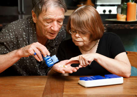 Senior couple at table with daily health supplementsの写真素材
