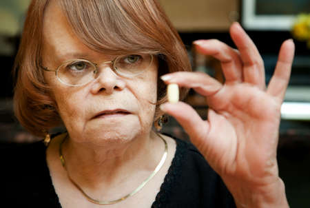 Senior woman holding daily health supplement tabletの写真素材