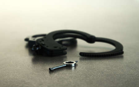 Handcuffs open on table with key in foregroundの写真素材