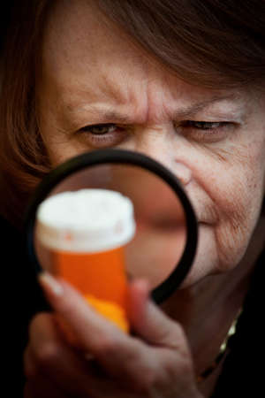 Woman closely examining prescription medication bottleの写真素材