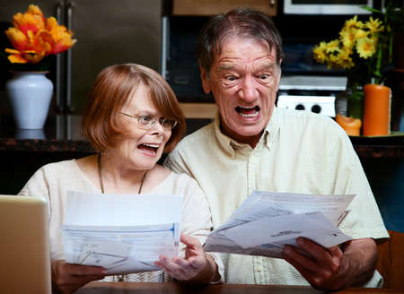 Senior couple at home reacting to many billsの写真素材