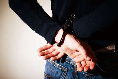 Closeup of hands cuffed behind young man's backの写真素材