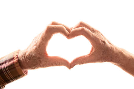 Senior couple forming heart by touching hands togetherの写真素材