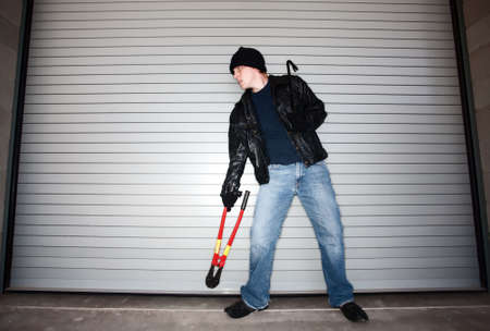 Burglar with tools in front of industrial doorの写真素材