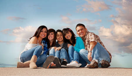 Hispanic family seated against a cloudy skyの写真素材