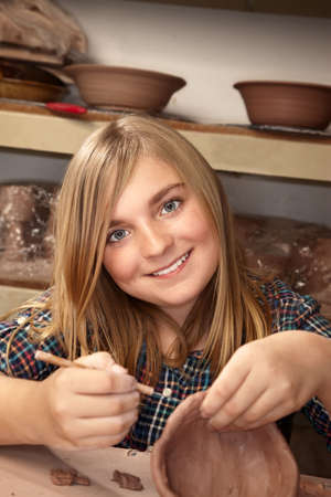 Cute young girl in clay studio working on a bowlの写真素材