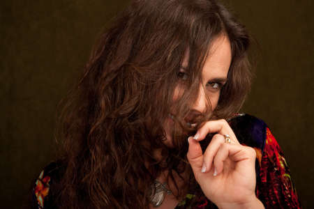 pretty woman in colorful blouse holding a bit of her hairの写真素材