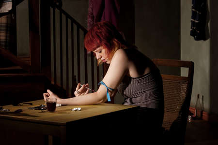 Woman wih tracks on her arm injecting heroinの写真素材