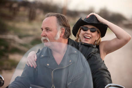 Mature couple riding on a motorcycle in the desertの写真素材