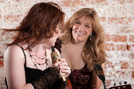 Woman sings along with guitar in front of a brick backgroundの写真素材