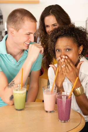 Three people at a cafe drinking frozen beverages. Vertical shot.