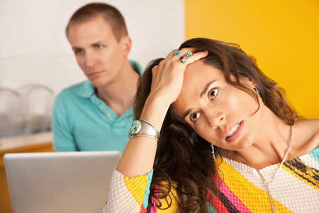 Image of a woman in the foreground with a frustrated expression while in the background a man is...
