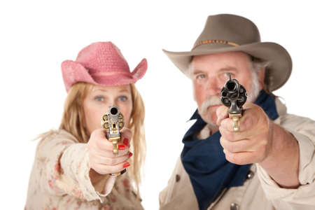 Couple in western wear pointing pistols with serious facesの写真素材