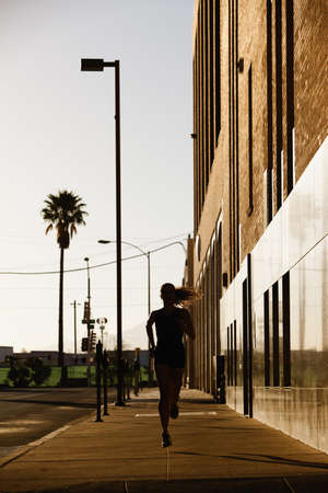 Beautiful woman jogs in the morning sunの写真素材