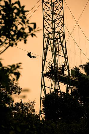 Silhoutte of tourists on zip line in Costa Ricaの写真素材
