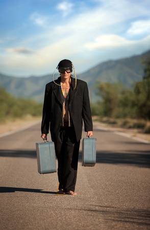 Strange indigenous man in the middle of a road with suitcasesの写真素材
