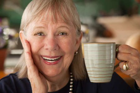 Senior woman at home with coffee or teaの写真素材