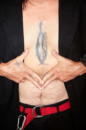 Mixed race man with feather tattoo on chestの写真素材