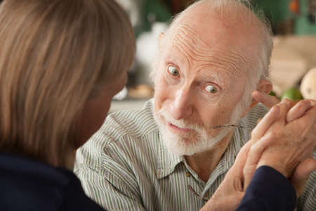 Senior couple at home in kitchen holding hands focusing on manの写真素材