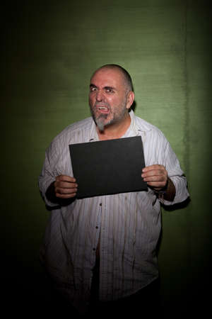 Strange man with beard and messy clothes takes a mugshotの写真素材