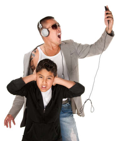 Hispanic youngster covers ears while father sings to music from an mp3 playerの写真素材