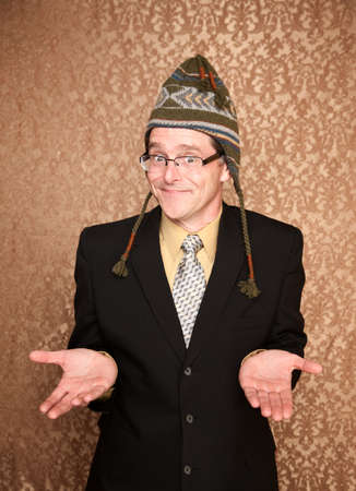 Businessman in black suit and a knit hat shrugsの写真素材