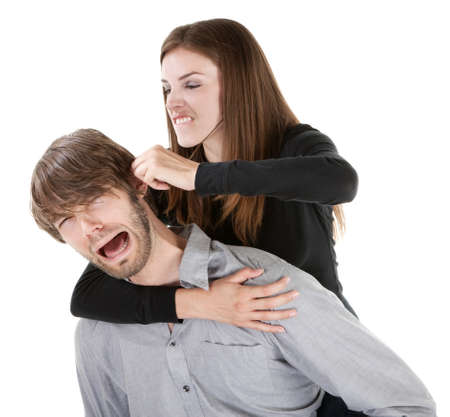 Beautiful Caucasian woman twisting boyfriend's ear while he screams